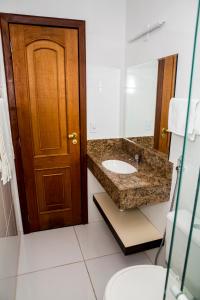 a bathroom with a sink and a wooden door at Executivo Flat II in Parauapebas