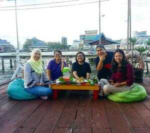 a group of women sitting around a table on a deck at Kunyit 7 Lodge in Bandar Seri Begawan