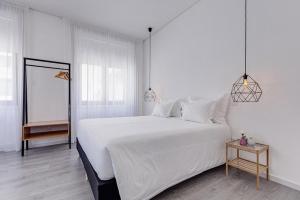 a bedroom with a large white bed and a table at Ovar Apartments by Aqualeisure in Ovar