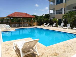 a swimming pool with chairs and a gazebo at Tropical Caribe in Bayahibe