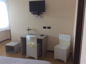 um quarto com uma secretária, 2 cadeiras e uma televisão em B&B Notte sul Lago em Gozzano