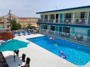 a swimming pool with umbrellas next to a hotel at Royal Court Motel in Wildwood