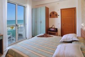 a bedroom with a bed with a view of the ocean at Hotel Cigno D'Oro in Riccione