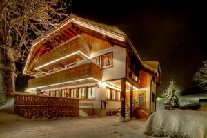 een huis wordt 's nachts verlicht in de sneeuw bij derWaldfrieden naturparkhotel in Herrenschwand