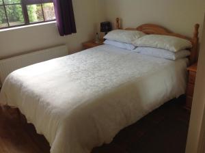 a bedroom with a large white bed with two pillows at Auntie B's in Ardara