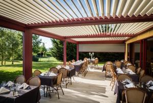 a restaurant with tables and chairs on a patio at Hotel Ambotel in Ambérieu-en-Bugey