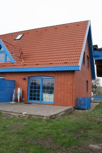 ein rotes Backsteinhaus mit einer blauen Tür und einer Terrasse in der Unterkunft Zur alten Schmiede I Links in Boltenhagen