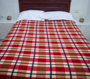 a bed with a colorful blanket on top of it at Hotel Pacifico Cerca al Aeropuerto in Palmira