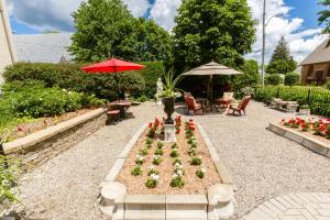 un jardín con sombrilla roja, mesa y sillas en Russell Manor Bed & Breakfast, en Morrisburg
