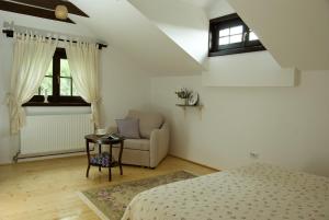 a bedroom with a bed and a chair and windows at Casuta cu prieteni in Cornu de Jos