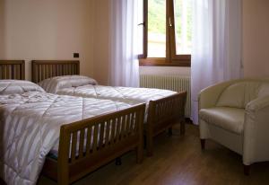 a bedroom with two beds and a chair and a window at B&B La Palanca in Revine Lago