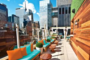 a rooftop patio with colorful chairs and tables and a city at Sanctuary Hotel New York in New York