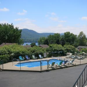 a swimming pool with chairs and a fence at The Austin Inn in Lake George
