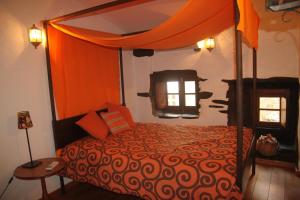 Aldeia Oliveiras في Sobreira Formosa: غرفة نوم مع سرير مع مظلة برتقال