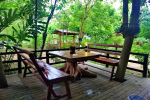 a wooden table and benches on a wooden deck at Baan Chanoknunt Resort Pai in Pai