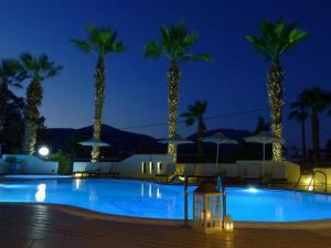 a pool at night with palm trees at Sun Rise Hotel Apartments in Eretria