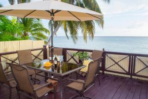 a table and chairs on a deck with an umbrella at Darrel Cot Beachfront Cottage in Saint Peter