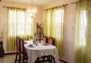 uma sala de jantar com uma mesa e cortinas amarelas em Darrel Cot Beachfront Cottage em Saint Peter