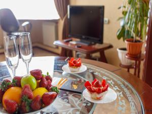 a table with strawberries and fruit on a table with wine glasses at Studio De Luxe with Jacuzzi in Sumy