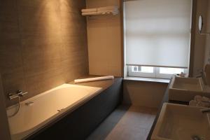 a bathroom with a tub and a window and a sink at Hotel Astel in De Haan