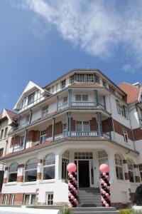 um grande edifício branco com decorações vermelhas em frente em Hotel Astel em De Haan