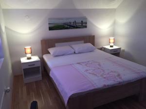 a bedroom with a bed with two nightstands and two lamps at Apartments Premović Nikšić in Nikšić