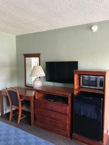 a living room with a television and a desk with a microwave at Economy Inn in Modesto