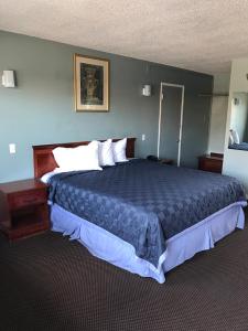 a bedroom with a large bed with a blue comforter at Economy Inn in Modesto