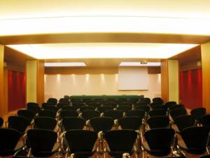 una sala conferenze con sedie, schermo e podio di Hotel Borghetti a Verona