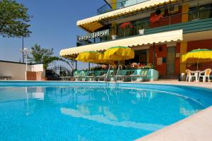 a swimming pool with chairs and umbrellas in front of a hotel at Hotel Jadran in Lido di Jesolo