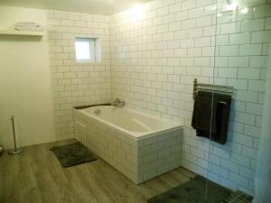 ein weiß gefliestes Bad mit einer Badewanne und einem Fenster in der Unterkunft La Gauviniere in Liez