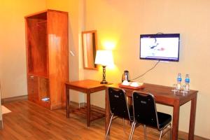 a room with a desk with two chairs and a television at Wakatobi Patuno Diving and Beach Resort by SAHID in Wanci +43 photos
