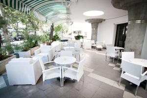 a restaurant with white tables and white chairs at Hotel ABC in Riccione