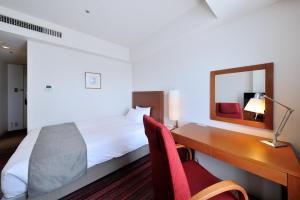 a hotel room with a bed and a desk at JR Kyushu Station Hotel Kokura in Kitakyushu