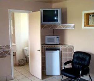 a room with a chair and a television on a wall at Pleasant Stay Motel in Ancaster