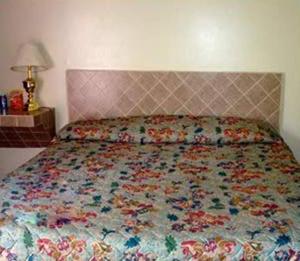 a bedroom with a bed with a floral quilt on it at Pleasant Stay Motel in Ancaster