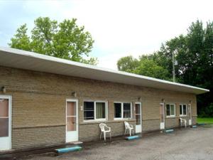 ein Gebäude mit zwei weißen Stühlen davor in der Unterkunft Pleasant Stay Motel in Ancaster