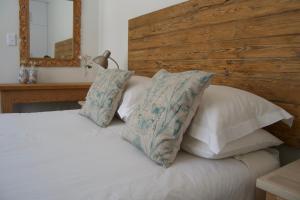 a bedroom with a white bed with pillows and a mirror at LA Guesthouse in Piet Retief