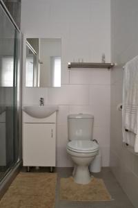 a white bathroom with a toilet and a sink at LA Guesthouse in Piet Retief