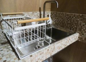 a kitchen sink with a metal dish rack next to it at Guest House Toranjyo-lit in Tamano