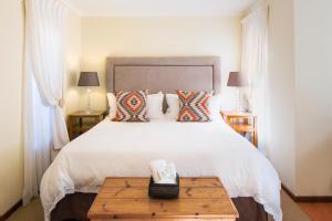 1 dormitorio con 1 cama blanca grande y mesa de madera en Kingfisher GuestHouse, en Port Elizabeth