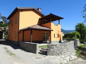 ein kleines gelbes Haus mit einer Steinmauer in der Unterkunft Počitniška Hiša in Dobravlje