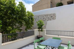 een balkon met een blauwe tafel en groene stoelen bij La Maison des Vendangeurs sur Mer in Gruissan
