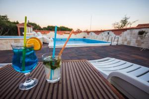 two drinks sitting on a table next to a pool at Villa Kata in Vrpolje