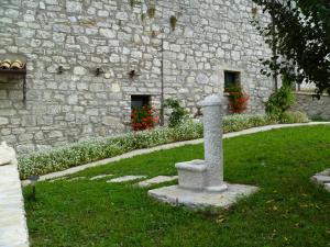 un pilier en pierre dans l'herbe à côté d'un bâtiment en pierre dans l'établissement Affittacamere La Casella, à Gallo