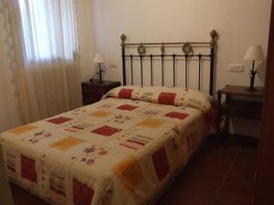 Una cama con edredón en un dormitorio en Casa La Rosa P.N. Sierra de Grazalema en Benamahoma