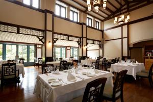 a dining room with white tables and chairs and windows at Hamilton Ureshino in Ureshino