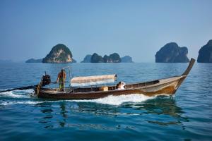 a man in a boat in the water with some islands at Cape Kudu Hotel, Koh Yao Noi - SHA Plus Certified in Ko Yao Noi