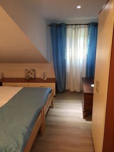 a bedroom with a bed and a desk and blue curtains at Apartment Retro III in Koper
