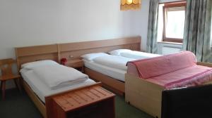 une chambre d'hôtel avec deux lits et une chaise dans l'établissement Garnì Astor, à Arabba